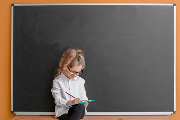 Canvas Print - Cute little schoolgirl near blackboard in classroom