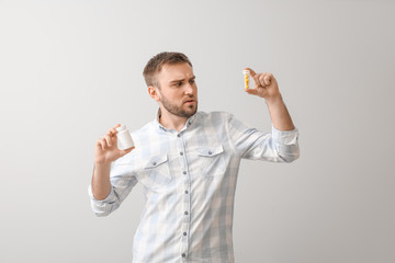 Poster - Young man with pills on light background