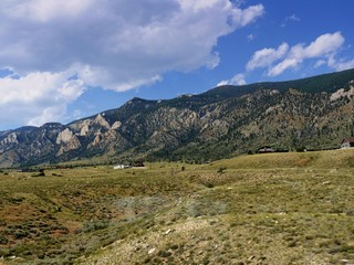 Beautiful views f Wyoming landscape, with thick white cottony clouds in the skies and cabins at the foot of the mountains.