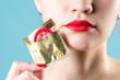 © Вячеслав Думчев - Close-up of a young girl's red lips and a red condom that peeks out of a package