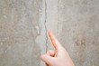 © fotoduets - Man hand finger pointing to cracked ceiling. Building problem and solution concept. Close up.