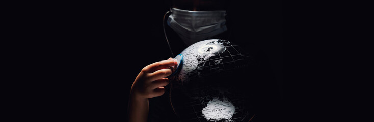 Wall Mural - hands of kid holding globe put stethoscope on sphere covid-19 pandemic infection disease