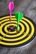 © Yury - Dart board with colorful darts, on a wooden table.