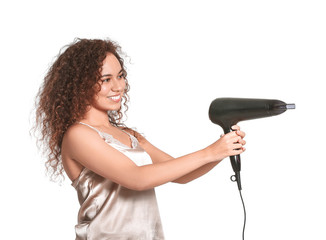 Wall Mural - Beautiful young African-American woman with blow dryer on white background