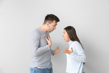 Poster - Young couple quarreling on light background