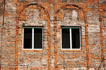 unplastered brick wall of a building with two windows