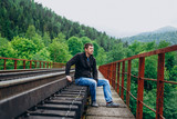 Fototapeta Miasto - Handsome man on railway track on forest background