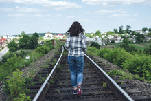 Young Woman In Jeans And Shirt Runs Along The Railway Track On A Sunny Day