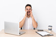 © luismolinero - Young business man with a mobile phone in a workplace shouting with mouth wide open