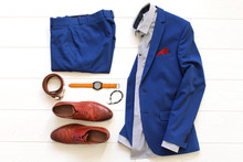 Flat Lay Set Of Classic Mens Clothes Such As Blue Suit, Brown Shoes, Belt, Watches And Bracelet On White Wooden Background.