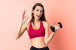 © luismolinero - Young sport woman making weightlifting over isolated pink background showing ok sign with fingers