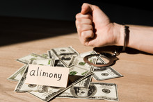 Selective Focus Of Handcuffed Man Near Dollar Banknotes And Paper With Alimony Lettering