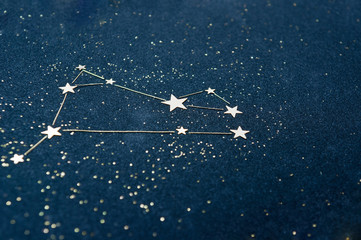 aries zodiac sign on the starry sky close up. application from star confetti and glitter black cardb