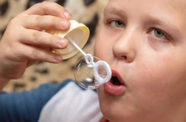 The boy blows up soap bubbles