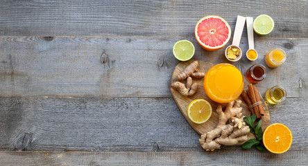 Top view on the immune system booster - orange juice, ginger, turmeric, citruses, and honey on the old wooden table