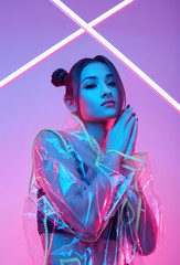 Wall Mural - Elegant beautiful woman in a raincoat around colourful bright neon