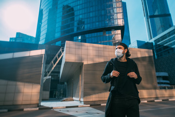 A man in a medical mask on an industrial background of skyscrapers