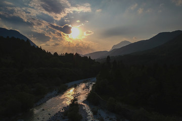 Beautiful summer evening with sun just setting down behnd julian alps and river in Resia region or Rezija, close to Resciutta village. Nearby villages of Oseacco and Solbica are nearby