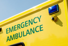 Ambulance Sign On The Side Of NHS Medical Response Vehicle, Against A Clear Blue Sky.