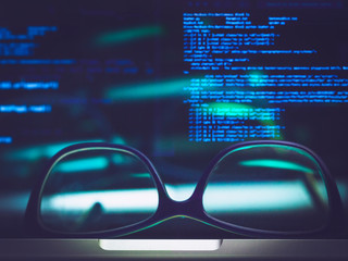 glasses and screen with code in background
