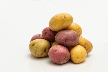 Pile of red and yellow bite size potatoes over white background