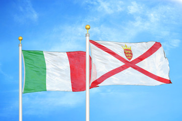 Italy and Jersey two flags on flagpoles and blue cloudy sky