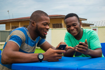 two young handsome african guys operating their cellphone.