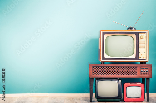 Retro classic old analog TV receivers set and aged wooden television stand with outdated amplifier front gradient mint blue wall background. Broadcasting, news concept. Vintage style filtered photo © BrAt82