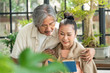 © CandyRetriever  - Relaxing Asian senior couple man and woman enjoy reading a book together in greenhouse garden at home. Retirement old age family having romantic moment. Elderly lifestyle and healthcare concept.