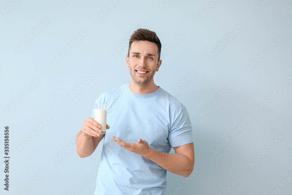 Young man with milk on color background