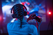 © Anton - Young girl in headphones plays a video game on a screen projector or TV in the room. Gamer with a joystick. Online games with friends, competitions. Fun entertainment. Teens play strategy. Back view