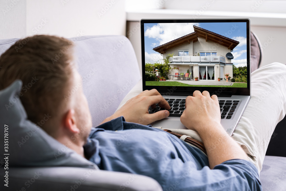 Man Selecting New House On Laptop At Home - obrazy, fototapety, plakaty 