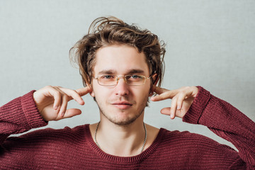 Closeup portrait young, angry, unhappy, stressed man covering his ears, looking up, to say, stop making loud noise it's giving headache. Negative emotions, face expressions