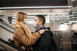 © snedorez - Side view of hugging couple in medical masks on escalator in subway.