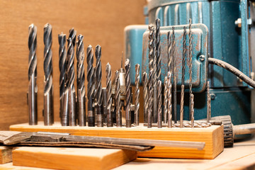 Set of different size drills standing in the box on working surface in workshop