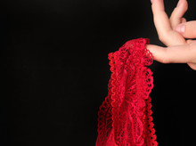 Red Lace Underwear In A Woman's Hand On A Black Background. Women's Secret