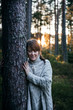 © Maria Bååth - Woman leaning against a tree and smiling during sunset in autumn