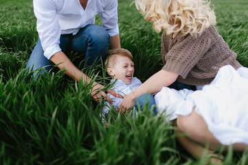  Family on a walk in a field with green grass and blue sky, early spring, good weather, happy family, white clothes