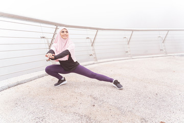 Active Muslim woman exercising on the bridge stock photo