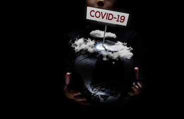Wall Mural - kid hands hold globe under cloudy sky covid-19 text, over black