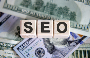 Seo concept. Wooden cubes and paper dollar bills as a background