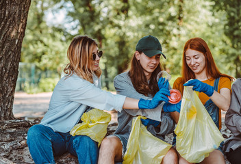 Group of activists friends collecting plastic waste at the park. Environmental conservation.