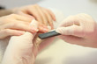 © White bear studio  - Closeup shot of a woman in a nail salon getting a manicure by a cosmetologist with a nail file. Woman gets a manicure of nails. Beautician puts nails on the client.