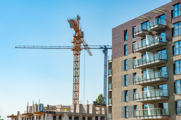 Fragment of luxury apartment building and construction site with cranes in the background