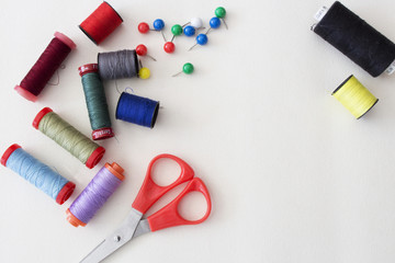 Sewing kit and colored threads on white background.