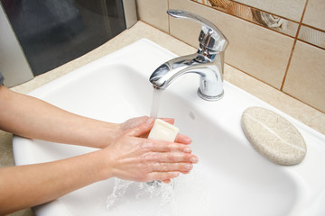 A Hands with soap are washed under the tap with water. Clean from infection and dirt and virus. At home or in the hospital ablution office.