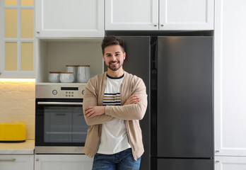 Poster - Happy young man near refrigerator in kitchen