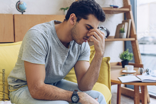 Fotografía Exhausted and tired man sitting on sofa in living room