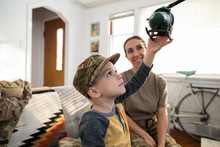 Soldier Mother Watching Curious Son Play With Toy Helicopter