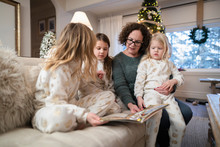 Grandmother Reading Bedtime Story To Granddaughters On Christmas